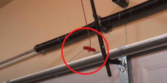 Thief attempting garage door fishing technique with wire coat hanger through weather seal